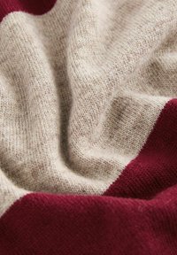 Pletená svetr fabric s krémovým podkladem a vínovými pruhy, jemná textura a drobné variace ve tloušťce příze.