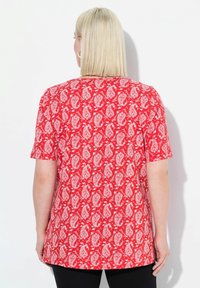Rood T-shirt met korte mouwen met een wit paisleypatroon. De achterkant heeft een losse pasvorm met een ronde halslijn en minimale stiksels.