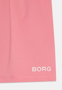Rosa idrettsminiskjørt laget av teksturert materiale. Har en hvit "BORG"-logo nær kanten. Kantlinjen er rett med enkel søm.