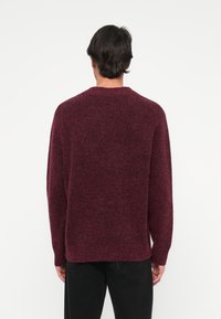 Burgundia ventsak, millel on tekstureeritud pind, ümar kaelus ja pikad varrukad. Omaduseks on lõdvenenud istuvus ning soonikkoes mansetid ja allserv.