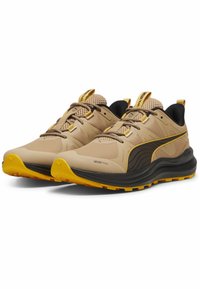 Beige and black trail running shoes with yellow accents, featuring a textured upper, reinforced toe cap, and gripped sole for traction.