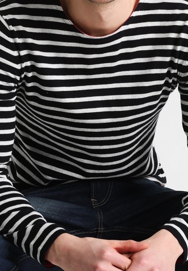 Chemise à manches longues à rayures noires et blanches avec un col rond, en tissu doux, assortie à un jean en denim foncé.