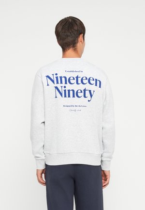 Gray crewneck sweatshirt featuring a large blue print on the back, reading "Established in Nineteen Ninety" and "Designed by the J&J crew."
