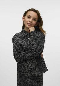 Veste en denim noir avec un imprimé léopard gris, dotée d'un col, de boutons sur le devant et de manches longues. Tissu texturé avec des coutures visibles.