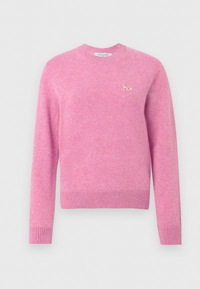 Różowy sweter z okrągłym dekoltem, z prążkowanymi mankietami i dolnym brzegiem, z małym wyszywanym logo lisa po lewej stronie klatki piersiowej.