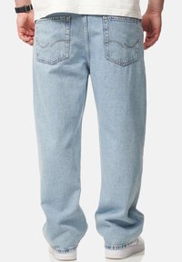 Light blue denim jeans with a relaxed fit, featuring two back pockets and subtle stitching detail. Reinforced hems and minimal texture.
