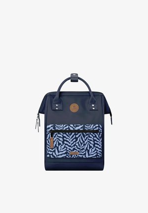 Zaino blu scuro con maniglie superiori, tasca frontale con cerniera decorata con motivo di foglie blu e bianche, e toppe del marchio in pelle marrone.