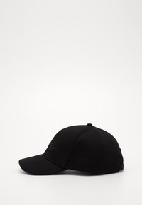 Casquette de baseball noire avec une visière incurvée, fabriquée en tissu texturé, présentant un logo en relief à l'avant et un bouton sur le dessus.