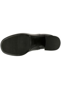 Svart skosula med ribbad textur. Liten klack med släta kanter. Platt profil, designad för komfort och stabilitet.