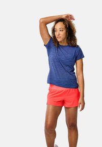 Krótki rękaw niebieskiej sportowej koszulki z heatherowym wzorem, zestawionej z jasnoróżowymi szortami. Lekki, oddychający materiał o luźnym kroju i prostym designie.