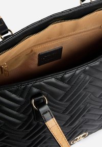 Borsa nera in pelle trapuntata con accessori dorati e interno color cuoio. Dotata di chiusura con cerniera e tracolla removibile con dettagli.