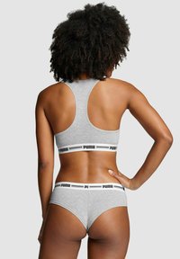 Grau Sport-BH und passende Unterhosen mit schwarzen Akzenten. Der BH hat ein Racerback-Design; die Unterwäsche verfügt über einen elastischen Bund mit Logo.