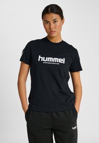 Sort bomulds T-shirt med et hvidt logo, der har teksten "hummel" og "SPORTSWEAR SINCE 1923", klassisk rund halsudskæring og korte ærmer.