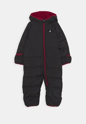 Sort, puffy one-piece dragt med røde accenter, hætte og lynlås foran. Har vandrette syninger og en lille logo-patch på brystet.