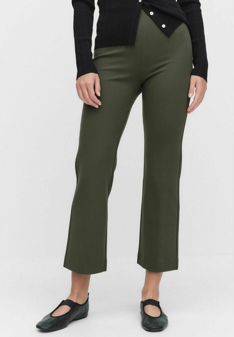 Oliivivihreät joustavat housut leveällä helmalla. Sujuva pinta, sopivan muotoinen malli, yhdistettynä mustaan ribbikardigaaniin ja ballerinoihin.