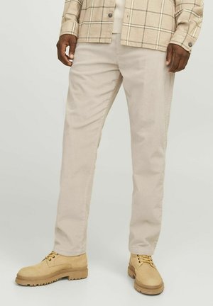 Beige corduroy pants with a vertical rib texture, tailored fit, paired with light brown lace-up boots for a casual look.