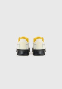 Witte en gele sneakers met een textuurontwerp, ronde vorm en zwarte rubberen zool, met gevoerde gele kraag en grijze accenten.
