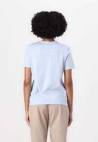 T-shirt en coton bleu clair à manches courtes, col rond et texture lisse. Présente une coupe droite et un design minimaliste.