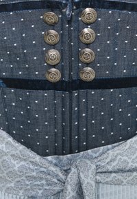Corset en denim avec des boutons argentés, motif à pois, et un tissu à motif bleu clair à la taille, avec des accents en velours à l'arrière.