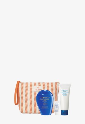 Stribet orange og hvid kosmetiktaske med blå SPF 50+ solbeskyttelseslotion, lille tube og hvid aftersun-helende emulsion.