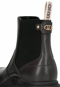 Braune Leder-Ankle-Boots mit elastischen Seiten, goldenen Hardware-Accents und einer Stoffzuglasche, die eine glatte Textur und ein elegantes Design aufweisen.