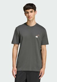 Tmavě šedé tričko s krátkým rukávem a kulatým výstřihem; na hrudi má malou, potištěnou grafiku v bílé a rezavé barvě. Hladká textilie.