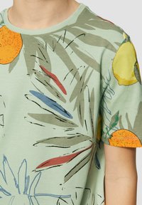 Korte mouwen groene T-shirt met een bladpatroon en illustraties van sinaasappels en citroenen, gemaakt van zachte katoen met een geribde halslijn.