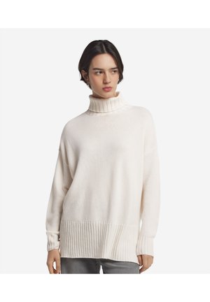 Polotröja i krämvitt med ribbade manschetter och nederkant, tillverkad av mjukt, texturerat tyg, med lös passform och nerfällda axlar.