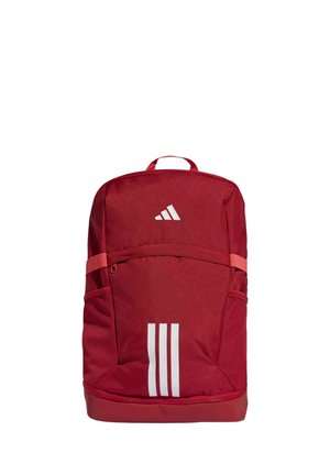 Zaino rosso Adidas con tre strisce verticali bianche sulla tasca frontale e logo Adidas sopra, dotato di tasche laterali in rete e maniglia superiore.