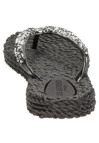 Ciabatta nera con suola in gomma textured, dotata di un cinturino trasparente decorato con piccoli elementi decorativi lungo la parte superiore.