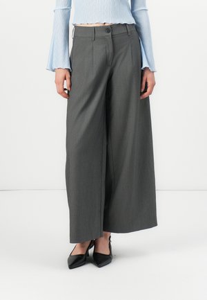 Brede pijpen broek van donkergrijze stof, met plooien aan de voorkant, een knoopsluiting en een gladde textuur, gecombineerd met zwarte pumps met een spitse neus.