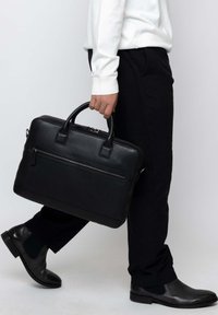 Black leather briefcase with dual handles and a front zipper pocket. Structured design, smooth texture, and minimal accents.