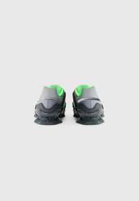 Grå sneakers med en mesh-overdel i et gittermønster, accentueret med livlige grønne detaljer og et markant gennemsigtigt såledesign.