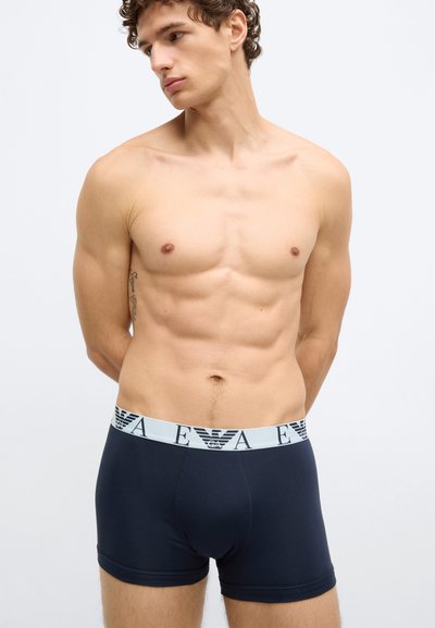 Tengerészkék boxeralsó elasztikus derékpánttal, logómintával. A szövet sima textúrájú és testhezálló kivitelű.