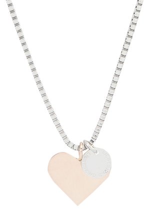 Collier en argent avec un pendentif cœur en or rose poli et une petite étiquette circulaire, tous deux attachés par un simple maillon.