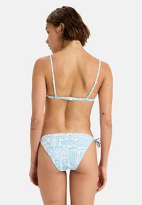 Světle modrý bikini s tenkými nastavitelnými ramínky a vzorovaným spodním dílem s květinovými motivy. Materiál vypadá hladký a elastický.