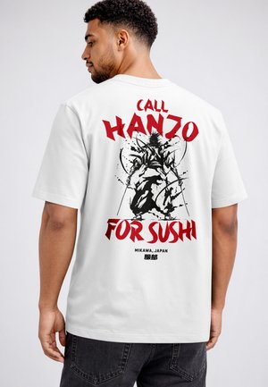 Man wearing white shirt with black ink-style samurai illustration and red text "Call Hanzo for Sushi" on back.