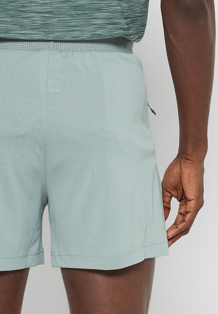 Los pantalones cortos deportivos de color verde claro cuentan con un material transpirable con textura perforada, una cinturilla elástica y un pequeño bolsillo lateral.