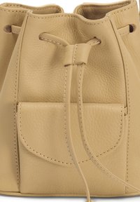 Sac seau en cuir beige avec fermeture à cordon, doté d'une poche frontale et de détails de coutures contrastantes. Matière douce et texturée.
