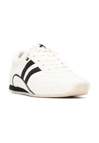 Zapatilla deportiva de cuero blanco con rayas negras, costuras texturizadas, punta redondeada, suela plana y diseño decordones. Acabado con un logo.