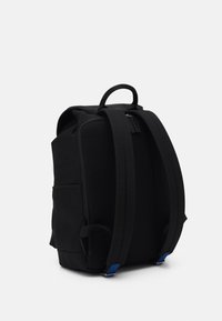 Sac à dos noir avec un dos en maille texturée, des bretelles rembourrées, une poignée supérieure et des accents bleus près de la base. Fermeture à glissière pour le compartiment principal.