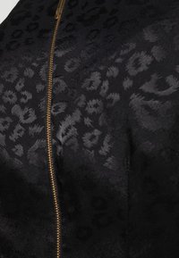 Black zip-up jacket featuring a subtle leopard print texture, accented with a gold zipper on the front. Soft material with a smooth finish.