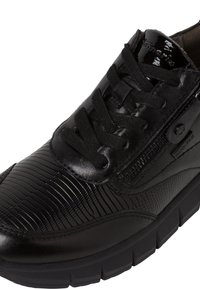 Sneaker nera con tomaia in pelle testurizzata, dettagli lisci, punta rotonda, lacci e zip laterale. Suola in gomma spessa per supporto.