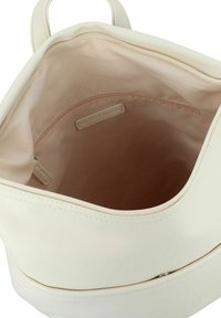 Bolso de mano color crema con un exterior liso y mate. El interior es de tela beis, con un bolsillo con cremallera y una etiqueta de marca cosida.