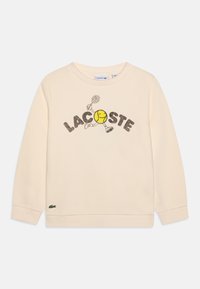 Crèmekleurige sweatshirt met de tekst "LACOSTE" en een speelse tennisbalgrafiek. Ribgebreide manchetten en zoom, met een klein logo op de onderste linkerhelft.