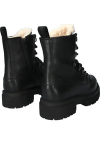 Zwarte leren enkellaarsjes met wollen voering, voorzien van een robuuste zool en metalen veteroogjes, met een opvallende ritssluiting aan de zijkant.