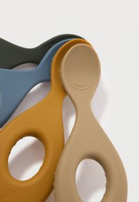 Τέσσερα σιλικονούχα εργαλεία σε ελαιοπράσινο, μπλε, χρυσό κίτρινο και μπεζ, με λεία υφή και οβάλ οπές, τοποθετημένα σε επικαλυπτόμενες θέσεις.