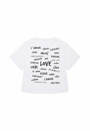 Witte T-shirt met korte mouwen waarop verschillende woorden voor "liefde" in meerdere talen zijn afgedrukt, in zwarte hoofdletters en kleine letters.