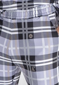 Leggings u višebojnom kariranom uzorku s crnom, sivom i bijelom bojom te zlatnim detaljima; elastična gumica u struku; oznaka branda.