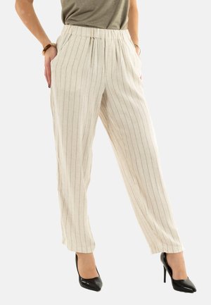 Pantalons en lin beige clair avec des rayures verticales noires, taille élastique et poches latérales, associés à des chaussures à talons hauts noires et brillantes.